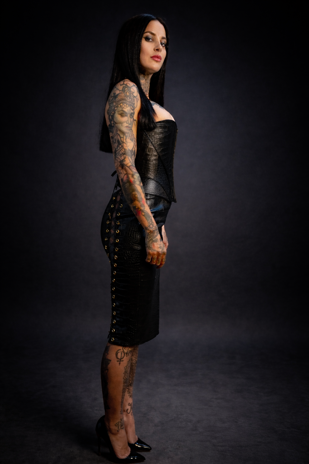 Woman wearing a black leather outfit with studded details on a dark background