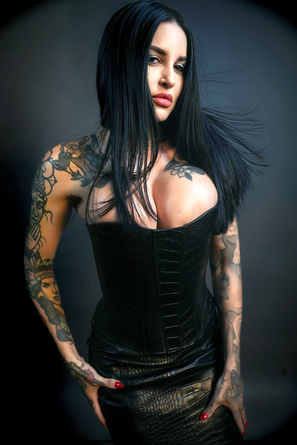 Woman with tattoos wearing a black leather outfit against a dark background