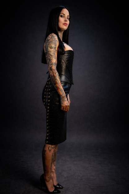 Woman wearing a black leather outfit with studded details on a dark background