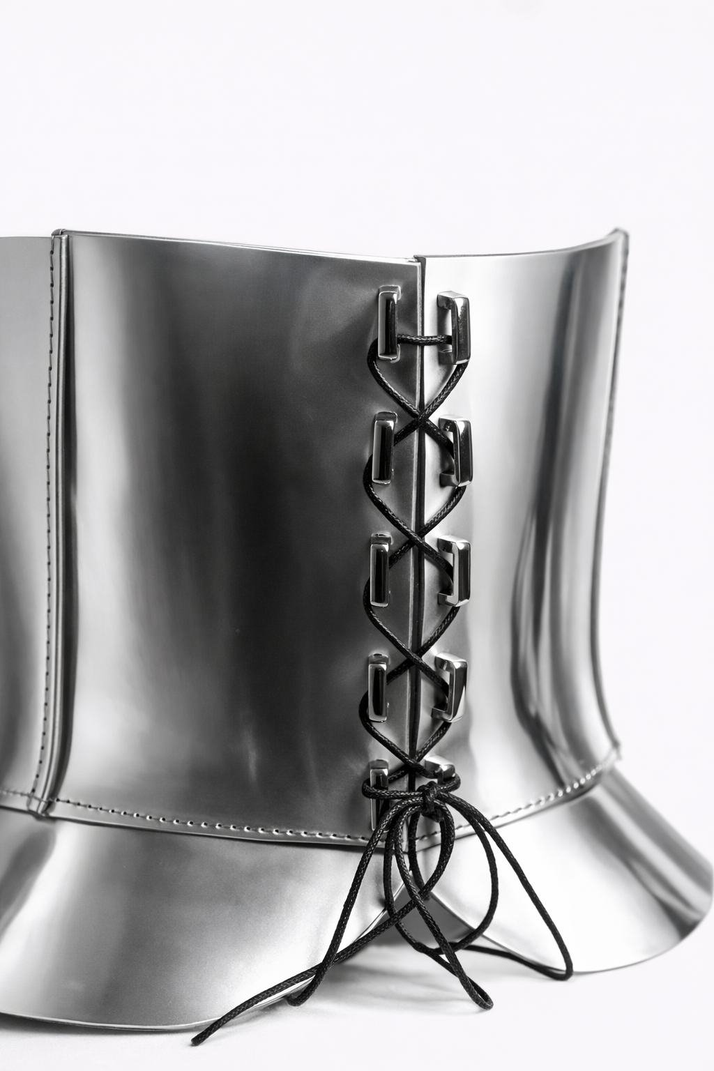 Silver metallic corset with black laces on a white background